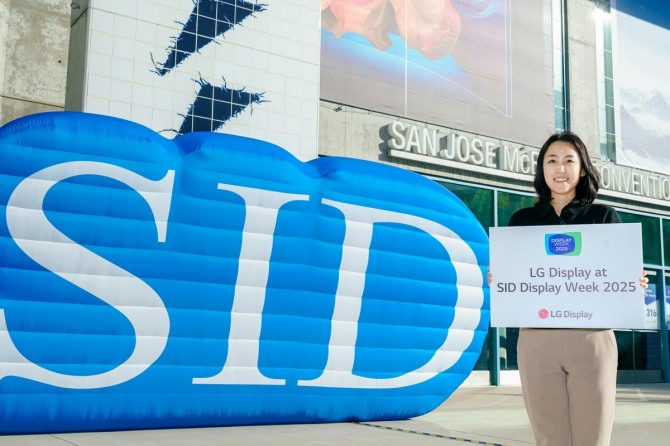 LG디스플레이 직원이 12일(현지시간) 세계 최대 디스플레이 전시회 'SID 2025'가 열리는 미국 새너제이 맥에너리컨벤션센터 앞에서 참가 소식을 알리고 있다. 사진=LG디스플레이