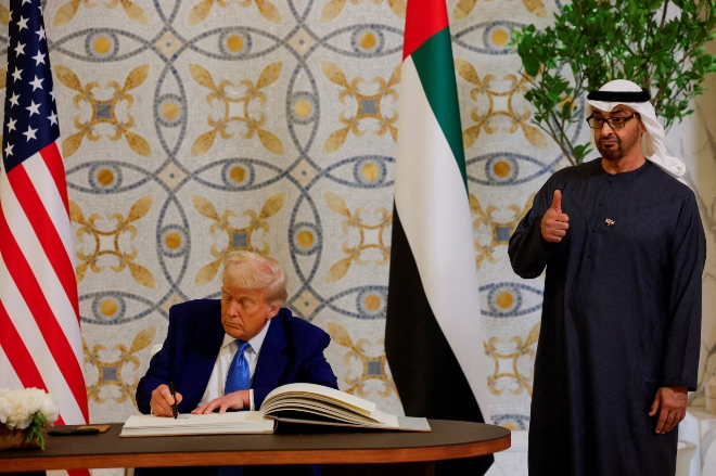 도널드 트럼프 미국 대통령(왼쪽)이 지난 15일(현지시각) UAE 아부다비의 카스르 알 와탄에서 무함마드 빈 자이드 알 나흐얀 UAE 대통령이 지켜보는 가운데 방명록에 서명하고 있다. 사진=로이터