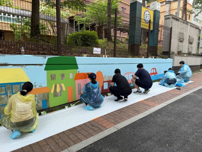 한국앤컴퍼니그룹 임직원과 가족들이 17일 용인·대전 소재 초등학교에서 벽화 그리기 봉사활동을 하고 있다. 사진=한국앤컴퍼니그룹