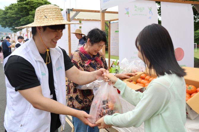 현대위아의 한 직원이 21일 경상남도 창원특례시 현대위아 본사에서 열린 ‘이음마켓’에서 지역 농가의 농산물을 사고 있다. 사진=현대위아 
