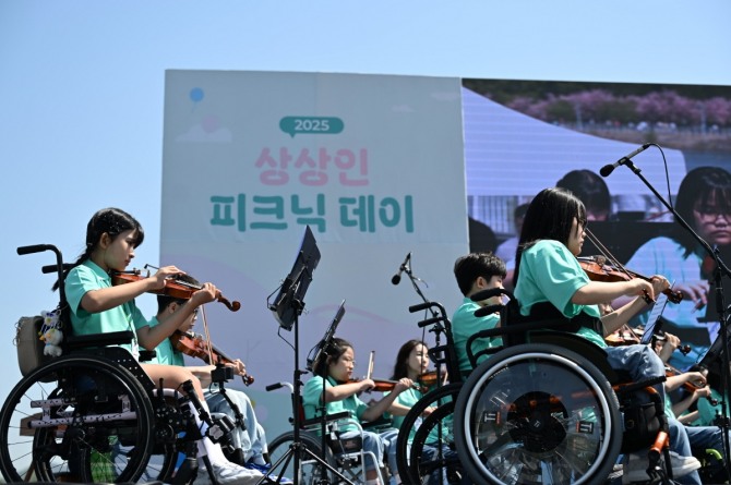 상상인그룹이 지난 4월26일 경기도 하남 미사경정공원에서 개최한 ‘2025 상상인 피크닉데이’에서 ‘상상휠하모니 오케스트라’가 축하 공연을 하고 있다. 사진=상상인그룹 제공.