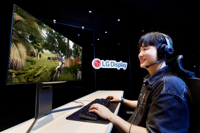 LG디스플레이 모델이 4세대 기술이 적용된 27인치 유기발광다이오드(OLED) 모니터 패널로 게임을 즐기고 있다. 사진=LG디스플레이