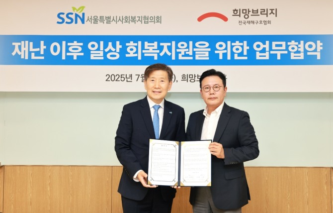 희망브리지 신훈 사무총장(오른쪽)과 서울시사회복지협의회 김현훈 회장이 재난취약계층 일상 회복지원을 위한 업무협약서에 서명한 뒤 기념촬영을 하고 있다.  /사진=희망브리지
