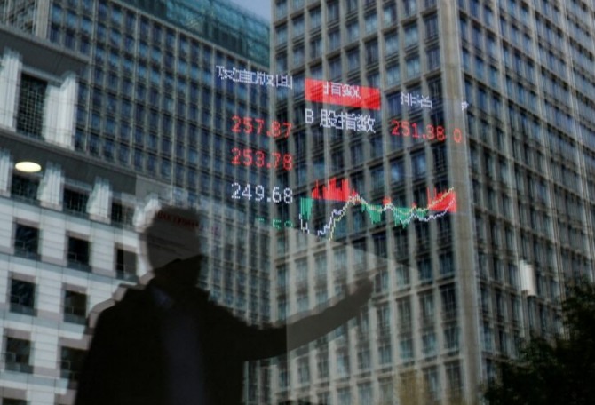 2025년 4월 9일 중국 베이징의 주가 지수 정보를 보여주는 전광판이 매달려 있는 증권사 유리에 사람과 건물이 비쳐지고 있다. 사진=로이터