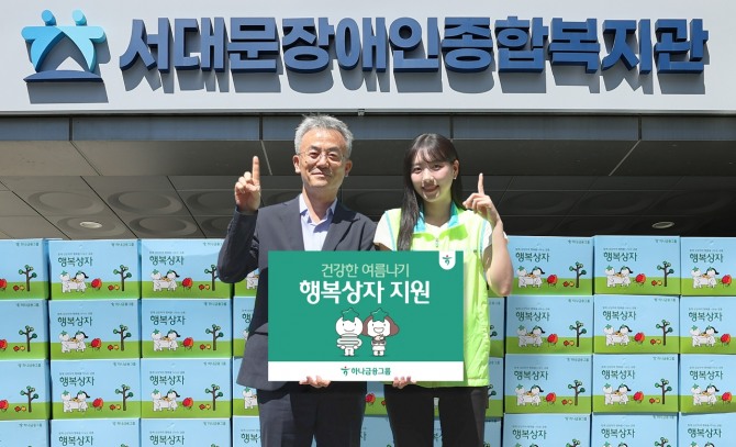 하나금융그룹은 연일 이어지는 폭염으로 어려움을 겪는 장애인 및 장애인 가족을 위해 폭염 대비 물품이 담긴 '건강한 여름나기 행복상자' 1111개를 전달했다. 이날 행사에 참석한 하나금융그룹 직원이 송용성 서대문장애인종합복지관장(사진 왼쪽)에게 행복상자를 전달하며 기념촬영을 하고 있다. 사진=하나금융그룹
