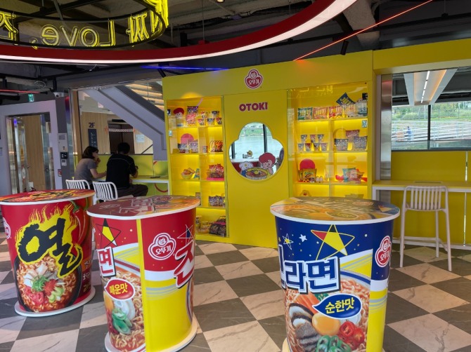 압구정 선착장의 ‘해피냠냠 라면가게’에 마련된 컵라면 모양 스탠드 테이블과 굿즈존. 사진=황효주 기자