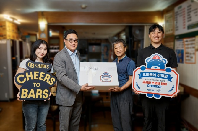 오비맥주 ‘우리동네 히어로’ 캠페인에서 선정된 사연의 업장 사장님이 오비맥주 임직원들과 함께 포즈를 취하고 있다. 사진=오비맥주