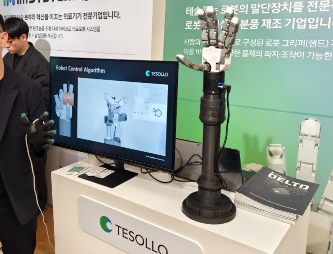 테솔로 부스에서 진행된 로봇팔 시연 모습. 검은 장감을 사용자가 착용하고 움직이면 로봇팔이 동일하게 움직인다. 사진=장용석 기자