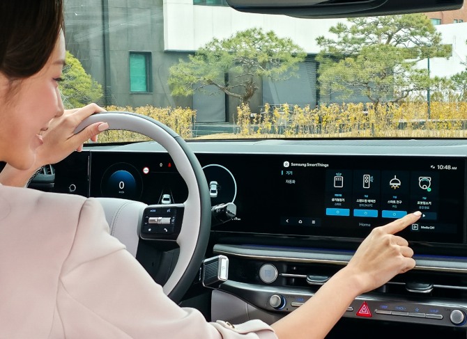 삼성전자 모델이 차량에서 집 안 가전기기를 제어하는 '카투홈(Car-to-Home)' 서비스를 체험하고 있다. 사진=삼성전자