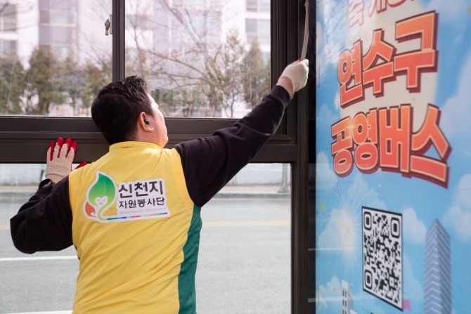 지난 29일 인천 옥련동 버스 승강장에서 신천지 자원봉사단 연수지부 봉사자가 유리면을 청소하고 있는 전경 사진=신천지 자원봉사단