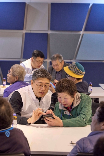 정재헌 SKT 대표가 경기도 포천시 관인노인대학에서 한 어르신 고객의 스마트폰을 살펴보고 대화를 나누는 모습. 사진=SKT