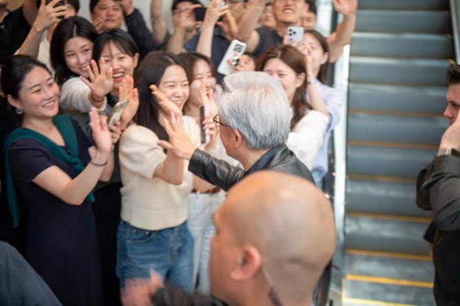 젠슨 황 엔비디아 CEO가 현대차그룹 임직원들과 하이파이브를 하면서 이동하고 있다. 사진=글로벌이코노믹