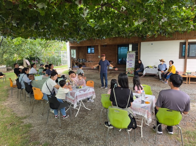 경산 진량읍 하늘농원에서 어린이와 보호자들이 포도가 자라는 과정과 재배 이야기를 듣고 있다. 경산시는 지역 대표 농산물인 포도를 생산 현장에서 직접 보고 수확하는 가족 농촌체험교육을 운영했다. 사진=경산시