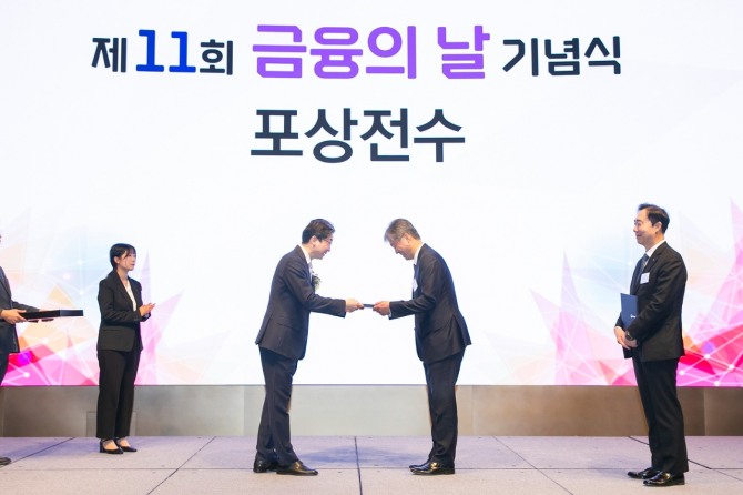 27일 오전 열린 ‘제11회 금융의 날’ 기념식에서 이억원 금융위원회 위원장(가운데 왼쪽)이 케이뱅크 최우형 은행장(가운데 오른쪽)에게 포용금융부문 금융위원장상을 수여하고 있다. 사진=케이뱅크